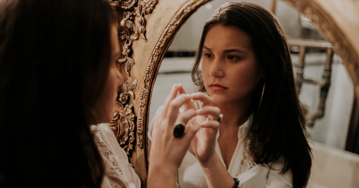 Jealousy Woman looking thoughtfully at her reflection in a mirror.